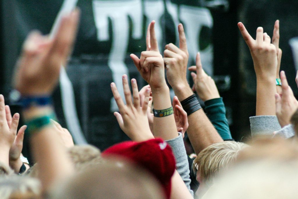 Group of people raising hands during a live concert in Nibe, Denmark, showing excitement and unity.